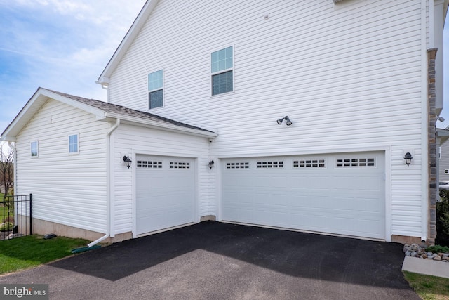 view of side of home featuring an attached garage and driveway
