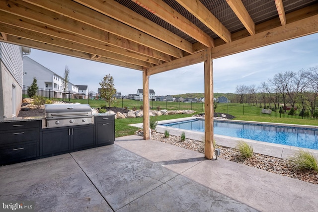 view of patio / terrace featuring grilling area, an outdoor kitchen, a fenced in pool, and a fenced backyard