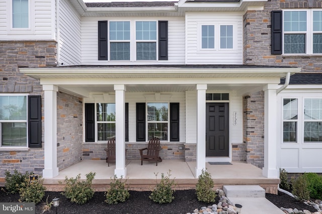 doorway to property with a porch and stone siding