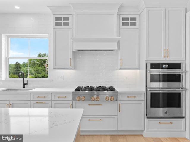 kitchen with decorative backsplash, white cabinetry, a sink, and appliances with stainless steel finishes