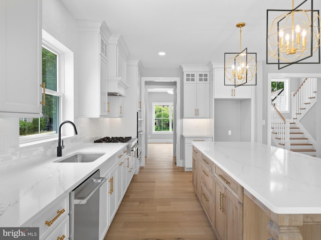 kitchen with a chandelier, a center island, backsplash, dishwasher, and a sink