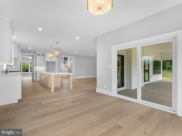 kitchen with light countertops, a sink, white cabinets, and light wood-style flooring