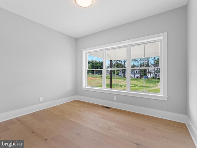 unfurnished room featuring visible vents, baseboards, and wood finished floors