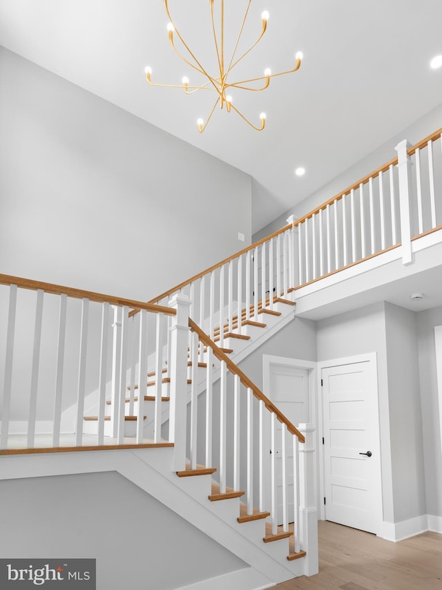 stairway featuring baseboards, an inviting chandelier, and wood finished floors