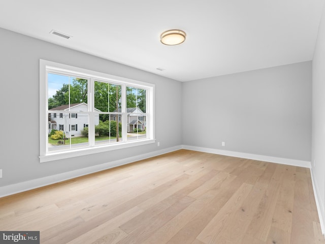 spare room featuring visible vents, baseboards, and light wood finished floors