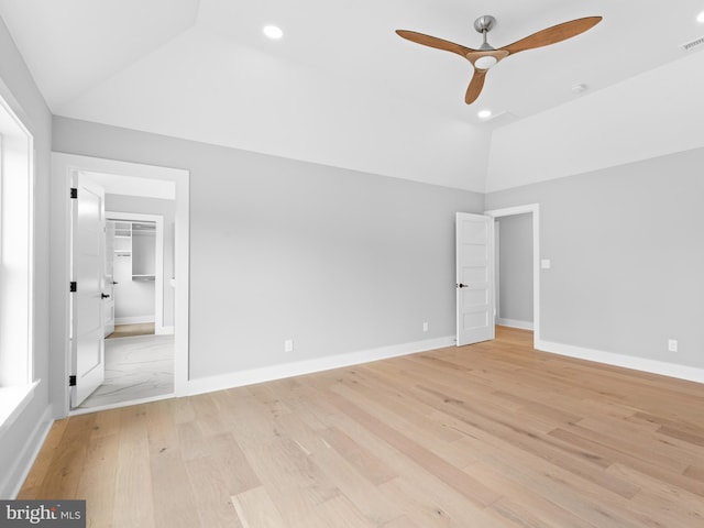 unfurnished bedroom featuring baseboards, vaulted ceiling, a spacious closet, recessed lighting, and light wood-style flooring