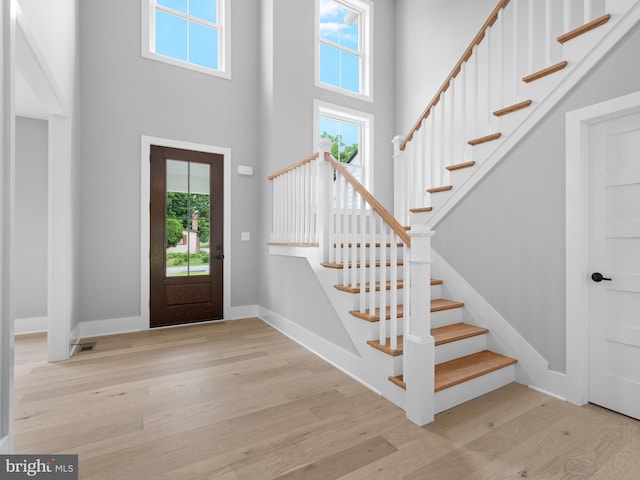 foyer featuring wood finished floors, a high ceiling, baseboards, and stairway