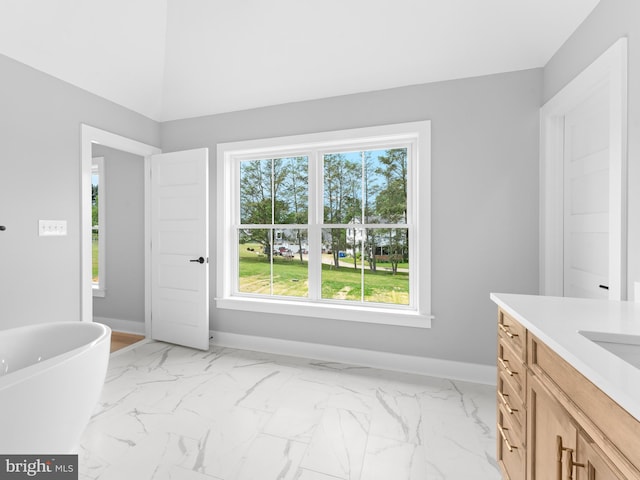 bathroom featuring a freestanding bath, vanity, marble finish floor, and baseboards