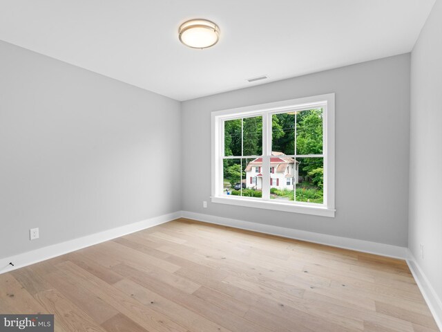 spare room with visible vents, baseboards, and wood finished floors