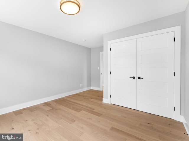 unfurnished bedroom with a closet, light wood finished floors, and baseboards