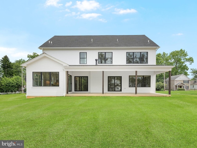 back of property featuring a yard, a shingled roof, and a patio