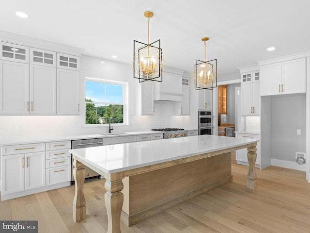 kitchen featuring an inviting chandelier, a sink, white cabinetry, stainless steel appliances, and a kitchen island