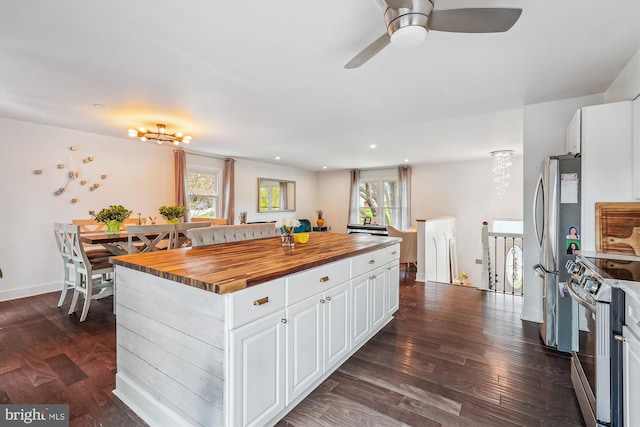 kitchen with ceiling fan, white cabinets, a kitchen island, stainless steel appliances, and butcher block countertops