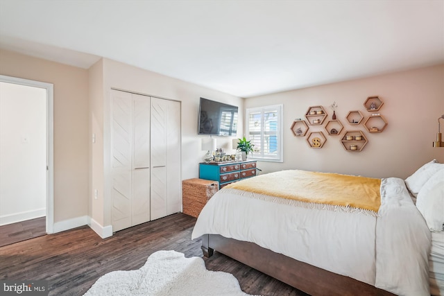 bedroom with a closet, baseboards, and dark wood finished floors