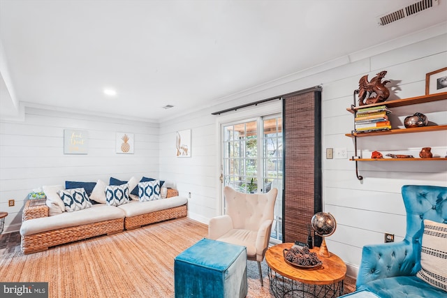 living room featuring ornamental molding, visible vents, and wood walls