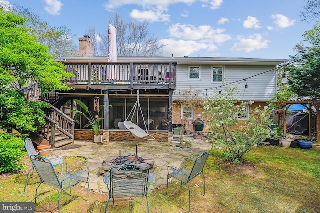 rear view of property featuring a sunroom, a patio, stairs, a chimney, and a deck