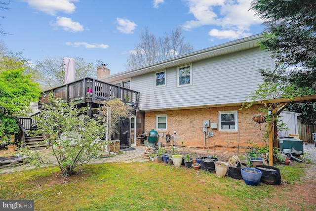 rear view of house with stairs, brick siding, a yard, and a deck