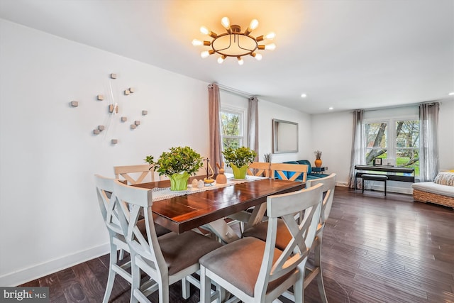 dining area with dark wood-type flooring, baseboards, plenty of natural light, and a chandelier