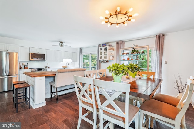 dining room featuring ceiling fan with notable chandelier and dark wood finished floors