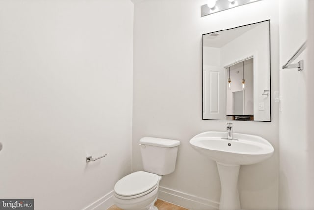 half bathroom with baseboards and toilet