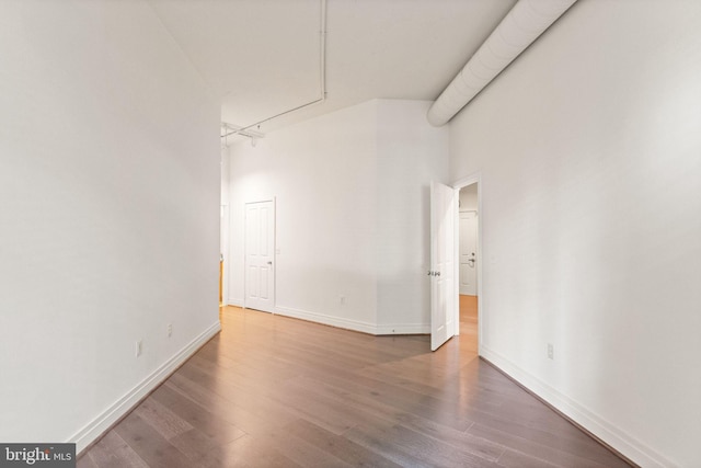 unfurnished room featuring wood finished floors, a towering ceiling, and baseboards