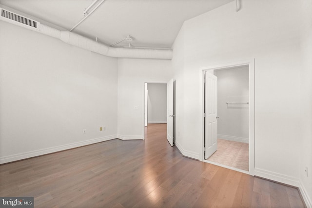 unfurnished bedroom featuring a walk in closet, wood finished floors, visible vents, and baseboards