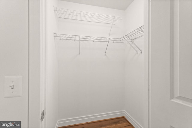 walk in closet with wood finished floors