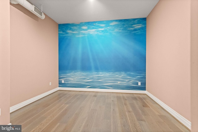 spare room featuring wood finished floors, visible vents, and baseboards
