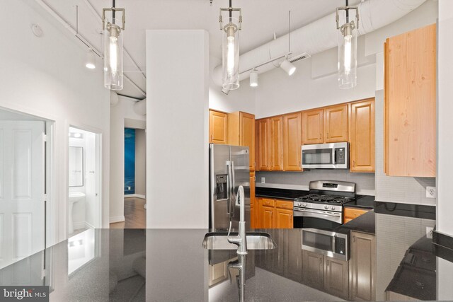 kitchen featuring dark countertops, hanging light fixtures, decorative backsplash, appliances with stainless steel finishes, and visible vents