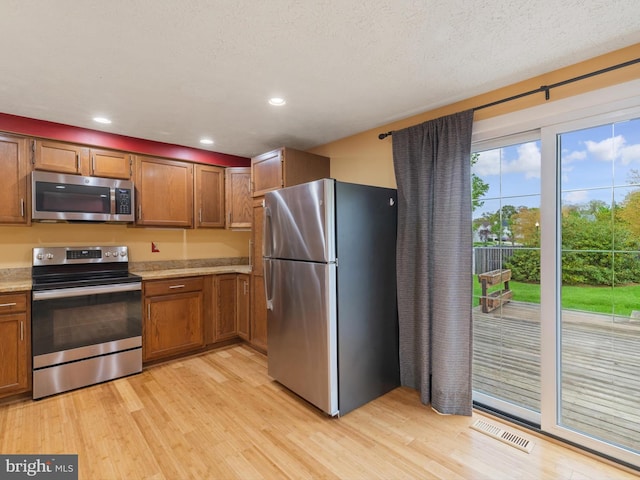 653 Willowby Run, Pasadena, MD 21122 - kitchen featuring brown cabinetry, light wood-type flooring, stainless steel appliances, light countertops, and visible vents