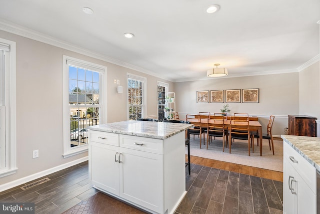 kitchen featuring a healthy amount of sunlight, ornamental molding, dark wood-style floors, and visible vents