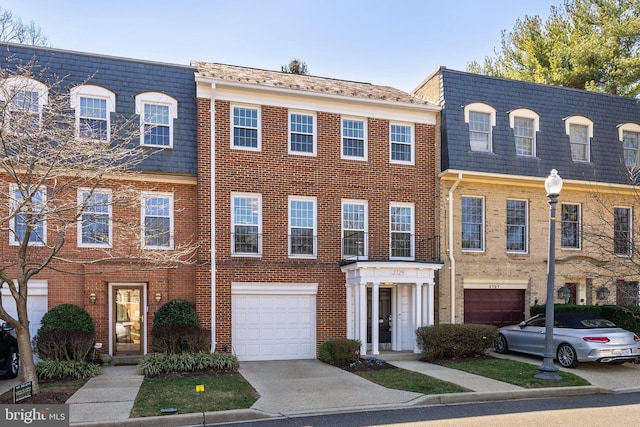 view of property with brick siding, an attached garage, driveway, and mansard roof