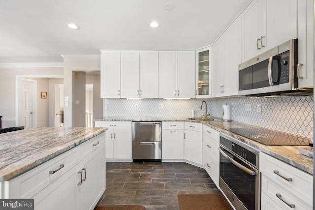 kitchen featuring decorative backsplash, light stone counters, glass insert cabinets, ornamental molding, and stainless steel appliances
