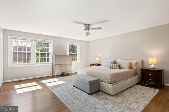 bedroom with baseboards, ceiling fan, wood finished floors, and visible vents
