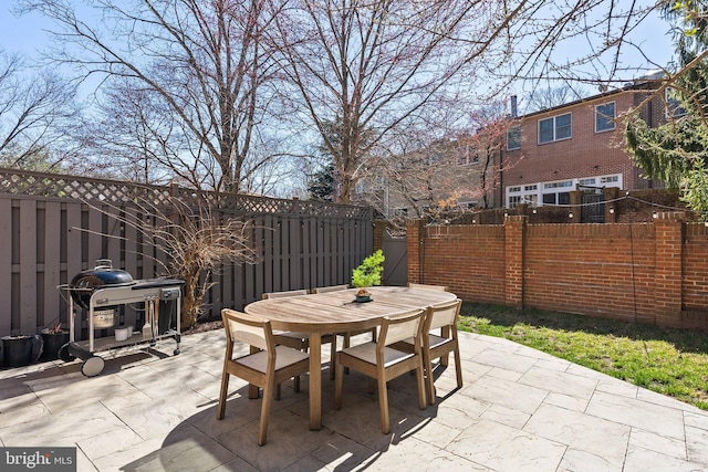 view of patio with grilling area, outdoor dining space, and a fenced backyard
