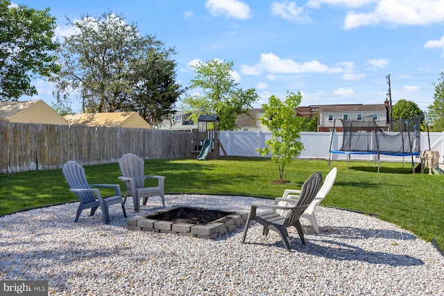 view of yard featuring a fire pit, a fenced backyard, a playground, a patio area, and a trampoline