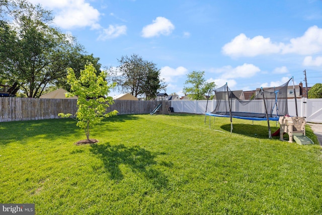 view of yard with a playground, a fenced backyard, and a trampoline