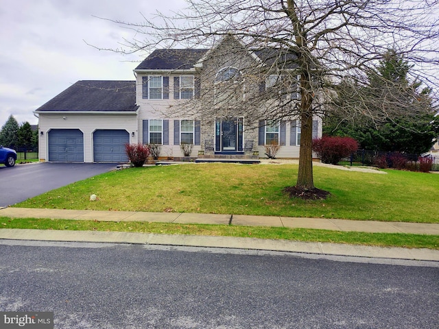 colonial house with an attached garage, a shingled roof, a front lawn, and aphalt driveway