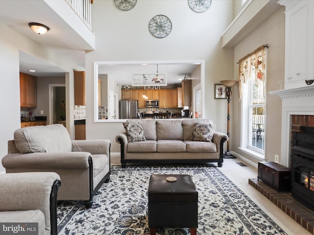 living room with light colored carpet, a high ceiling, baseboards, and a fireplace
