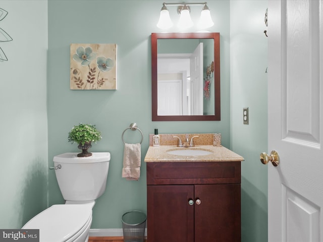 half bathroom featuring vanity, baseboards, and toilet