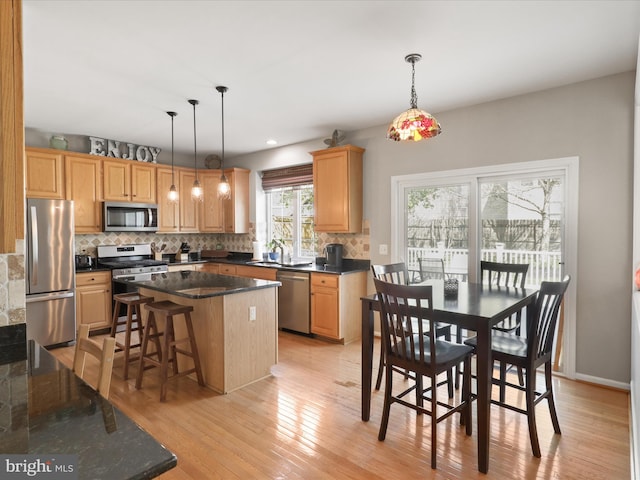 kitchen featuring stainless steel appliances, light wood-style flooring, backsplash, and a kitchen island