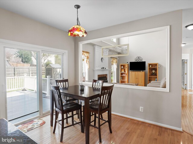 dining space with light wood-style flooring, baseboards, and a fireplace