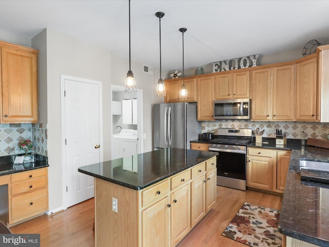 kitchen featuring a kitchen island, stainless steel appliances, decorative light fixtures, light wood finished floors, and backsplash