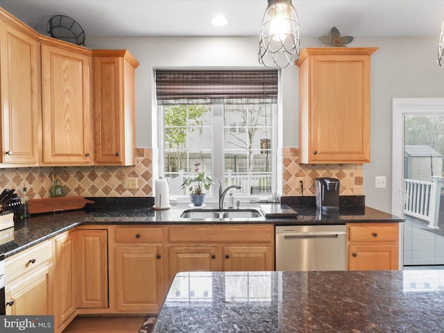 kitchen with a sink, stainless steel dishwasher, dark stone countertops, and a wealth of natural light