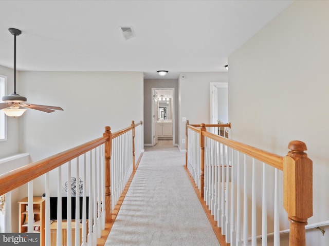 hall with an upstairs landing, visible vents, and baseboards