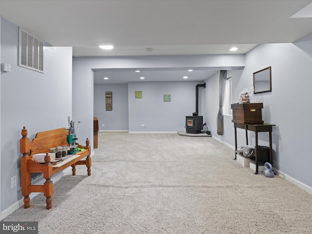 living area with a wood stove, carpet, visible vents, recessed lighting, and baseboards