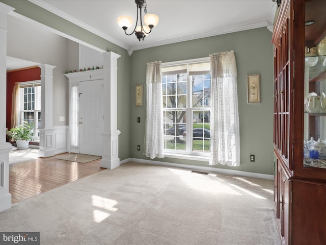 carpeted entryway featuring a notable chandelier, visible vents, ornate columns, and crown molding