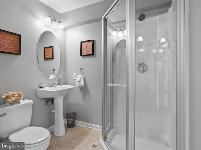 full bathroom featuring baseboards, tile patterned flooring, toilet, a shower stall, and a sink