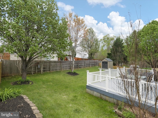 view of yard featuring a fenced backyard, a wooden deck, an outbuilding, and a storage unit