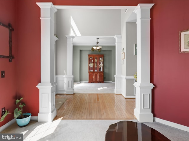 foyer featuring a chandelier, light wood-style flooring, and ornate columns